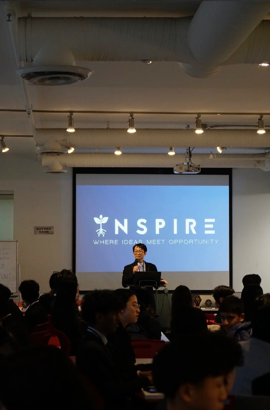 The opening address, with the Inspire logo on the screen behind the speaker