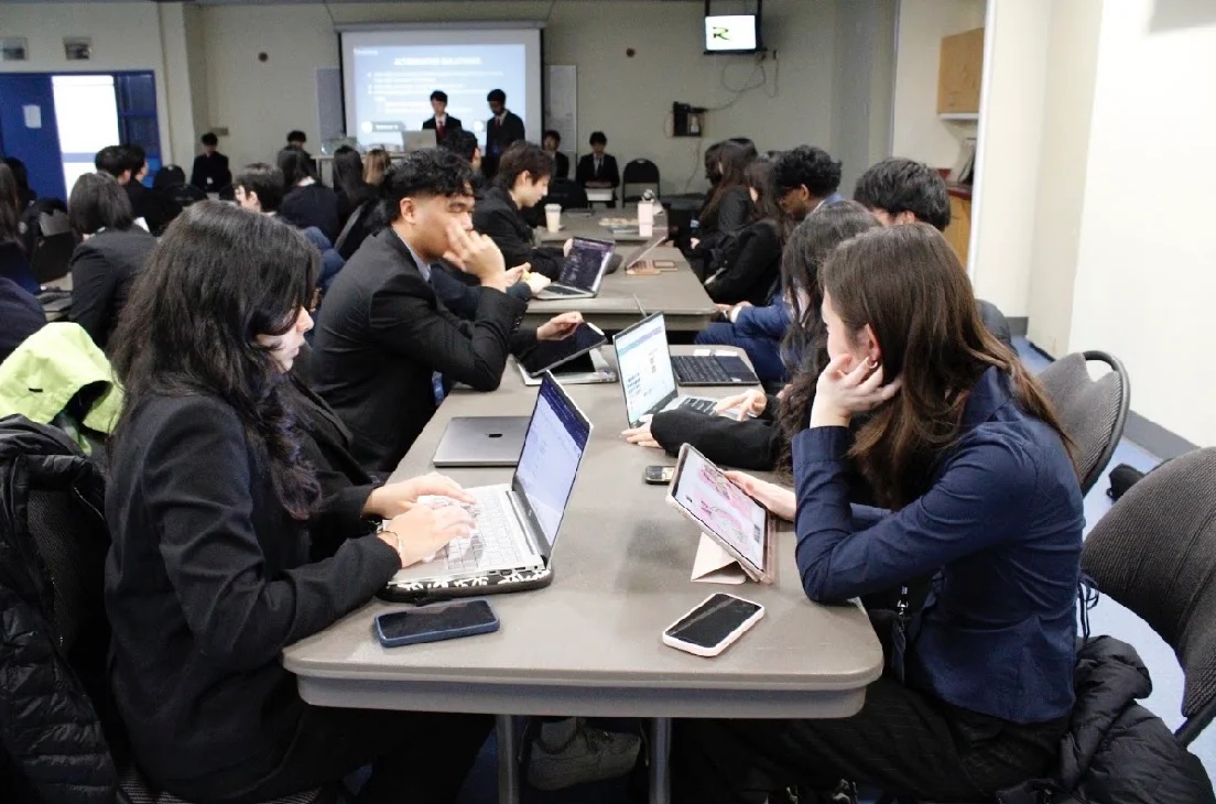 Teams at the long tables with their laptops open